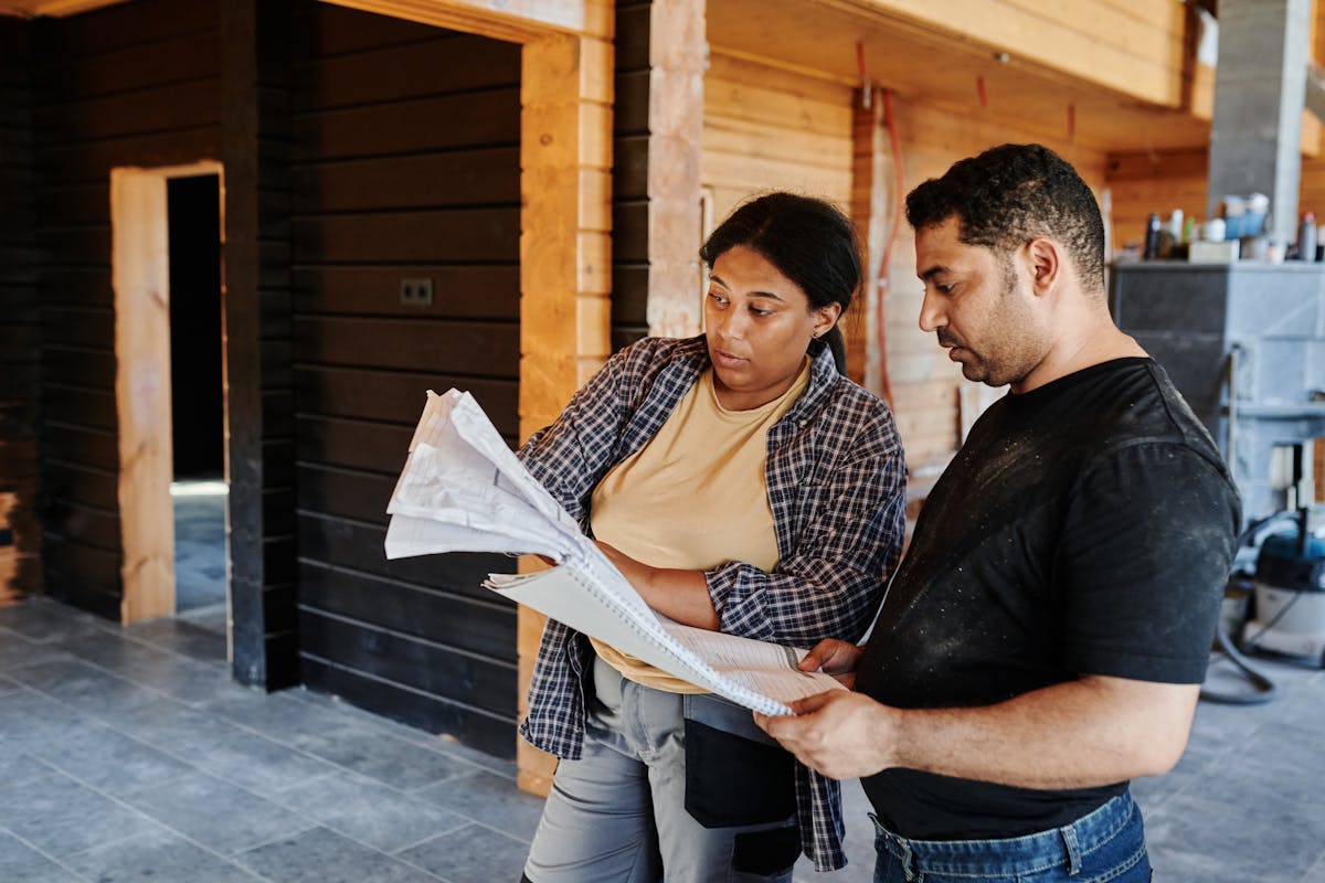 Two builders reviewing construction plans and blueprints